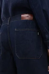 Pantalón de jean de corte wide leg en color azul oscuro, con tiro medio y cierre frontal con botón y cremallera.