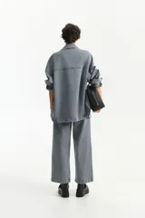 Sobrecamisa amplia de denim celeste con textura de rayas verticales, cuello camisero, cierre frontal de botones y dos bolsillos de parche con tapa en el pecho.