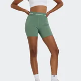 Short deportivo ajustado de tiro alto, color verde salvia, con banda elástica en la cintura que lleva el logo de New Balance repetido.