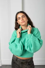 Polera de punto color verde menta, con cuello alto, mangas globo y diseño de trenzas en el frente.