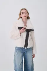 Tapado corto de piel sintética en color crema, con solapas amplias y cierre frontal asimétrico con detalles en cuero sintético oscuro.