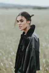 Campera oversize de cuero tostado con solapas y forro interno de corderito sintético azul marino, mangas anchas y detalles de costuras trenzadas.