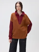 Pullover de tejido acanalado grueso con diseño bicolor en tonos marrón y bordó. Presenta cuello alto con cierre frontal, mangas largas y corte holgado.