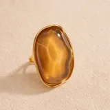 Anillo de diseño llamativo con base dorada y piedra central de resina en tono ámbar con textura orgánica.