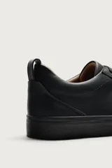 Zapatillas de cordones de estilo minimalista, color negro, con diseño liso, horma redonda, forro interior en tono contrastante y suela de goma texturizada.
