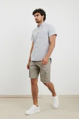 Camisa de manga corta a rayas verticales blancas y celestes, con cuello abotonado y bolsillo en el pecho.