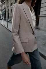Blazer de corte sastrero confeccionado en tejido de lana con diseño de espiga. Presenta cuello con solapas, hombreras, cierre frontal con un botón y bolsillos delanteros con solapa.