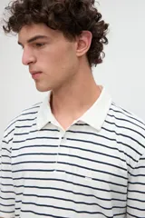 Remera polo de manga corta con diseño a rayas horizontales marrones sobre base blanca, cuello camisero en color blanco con media cartera de botones y aberturas laterales en el dobladillo.