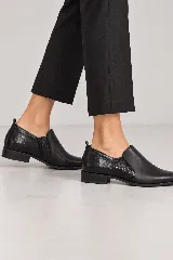 Botín bajo de cuero negro con diseño slip-on, con terminación lisa en la parte delantera y textura símil cocodrilo en el talón.