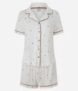 Pijama corto de dos piezas confeccionado en viscolycra blanca con estampado floral y vivo en contraste. Incluye una camisa de manga corta con cuello solapa y cierre frontal de botones, y un short con cintura elástica.