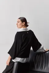 Sweater de punto liviano negro, con escote bote y mangas amplias de largo tres cuartos que aportan una silueta relajada y fluida.