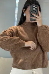 Buzo de chenille color marrón, con cuello alto, mangas largas con puños ajustados y ruedo acanalado.