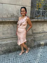 Conjunto de dos piezas compuesto por un top de un solo hombro con volados y una falda corta con ruedo asimétrico, confeccionado en tela satinada con estampado floral en tonos verde y dorado.