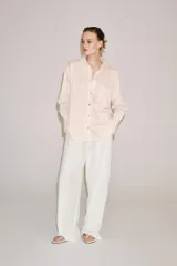 Camisa de mezcla de viscosa, color beige con rayas verticales rosadas, cuello solapa, manga larga con puños anchos, bajo redondeado y cierre frontal con botones.