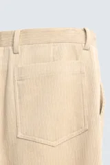 Pantalón de corte regular fit confeccionado en pana de algodón color beige, con bolsillos frontales, bolsillos traseros de plastrón y cierre frontal con cremallera y botón.