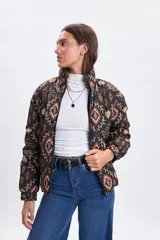 Campera puffer de abrigo con cierre frontal, cuello alto y puños elásticos. Presenta un diseño estampado con motivos geométricos y florales en tonos tierra sobre fondo negro.