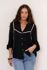 Camisa negra de manga larga con detalles de costuras y ribetes en color crudo, escote en V y cierre frontal con botones.