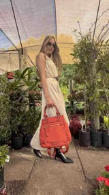 Cartera mochila de diseño versátil, color rosado, confeccionada en material sintético impermeable. Cuenta con doble asa superior, correas ajustables para usar como mochila, compartimento principal con cierre y bolsillo frontal con cierre decorado con tirador largo.