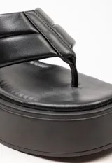 Sandalia tipo ojota con plataforma, confeccionada en material sintético color blanco. Presenta una tira ancha acolchada con detalle de costura central y diseño de separación para el dedo.