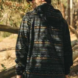 Canguro con cierre frontal completo, confeccionado en micropolar térmico. Presenta un diseño estampado con motivos étnicos en tonos azules, negros y ocres, con capucha y bolsillos laterales.