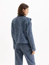 Chaqueta de denim Panamá azul de 100% algodón, con volados en el frente y cuello de cuero vacuno negro contrastante. Cuenta con bolsillos frontales con solapa y cierre de botones metálicos.