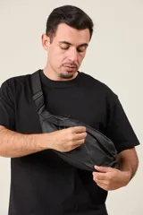 Riñonera negra de tela impermeable con correa ajustable con hebilla.