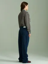 Camisa de viscosa con estampado a cuadros de estilo retro en tonos beige, azul marino, celeste y rojo. Presenta cuello camisero, cierre frontal con botones metálicos plateados y diseño con capas superpuestas en el pecho de inspiración country.