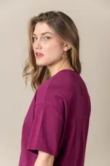 Remera gris con estampa de la letra M en negro y cadena plateada en el cuello.