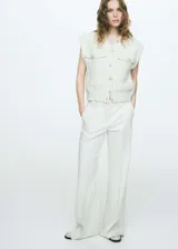 Chaleco color crema con textura tweed, cuello redondo, cierre frontal con botones dorados y dos bolsillos de parche con botón.