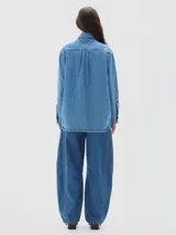 Camisa de denim de corte recto y estilo clásico, confeccionada en tejido de algodón con acabado lavado. Presenta cuello camisero, cierre frontal con botones metálicos y mangas largas con puños abotonados.