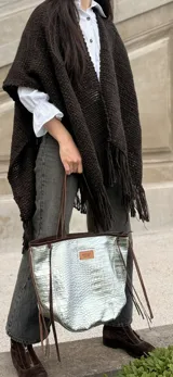 Cartera tipo tote de cuero color suela, con textura grabada tipo cocodrilo en el frente y laterales de gamuza. Cuenta con doble asa de hombro, detalles de costuras visibles, flecos decorativos laterales y cierre interno.