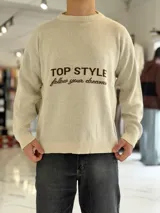 Sweater de punto color beige con cuello redondo, manga larga y diseño estampado en el pecho con las frases "TOP STYLE" y "follow your dreams" en color marrón.