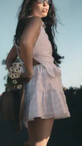 Top halter de broderie blanco con sutil brillo plateado, presenta cuello alto con volados y ruedo con volado amplio. Diseño sin mangas, femenino y ligero.