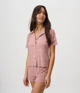 Pijama de dos piezas confeccionado en microfibra color rosado, con estampado geométrico. Incluye camisa de manga corta con cuello con solapa, cierre frontal con botones y detalles de encaje en las mangas, y short con cintura elástica.