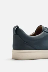 Zapatilla de cordones color beige, con parte superior lisa, horma redonda, forro interior a contraste y suela con ligera textura.