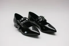 Zapatos tipo Mary Jane negros de charol con punta fina y dos tiras horizontales con hebilla plateada.