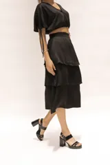 Falda midi negra de seda con cierre invisible lateral, elástico en la cintura y volados.
