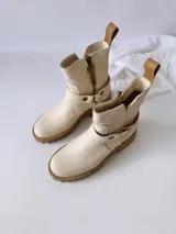 Botas cortas color crudo de cuero, con cierre lateral, pulsera desmontable y suela marrón.