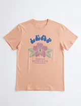 Remera de manga corta color naranja con estampa frontal que incluye la palabra 'LEAP' en letras azules y una flor de hibisco en tonos rosados y verdes.
