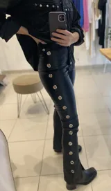 Pantalón marrón acampanado de gabardina elastizada con ojalillos metálicos en los laterales.