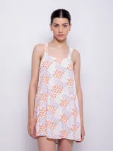 Vestido corto blanco con estampado floral en tonos naranja y lila, de corte suelto y sin mangas.