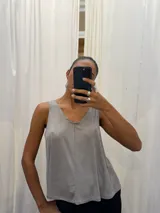 Musculosa de corte holgado con acabado brillante sutil, escote en V y costura central vertical. Presenta breteles anchos y un diseño acampanado hacia el ruedo.
