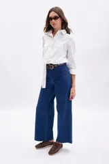 Pantalon de jean azul de corte ancho y tiro alto, con costuras a la vista y cierre frontal con boton y cremallera.