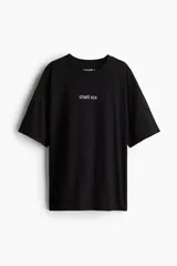 Remera de corte oversized confeccionada en algodón, con cuello redondo acanalado y hombros caídos. Presenta un estampado minimalista con el texto 'charli xcx' en el centro del pecho.