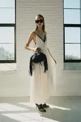 Vestido midi de satén color crudo, con escote en V, tirantes finos y detalle de lazada en el delantero.