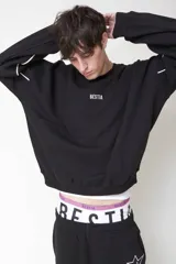 Buzo negro de corte holgado con cuello redondo y detalle de línea blanca curva en las mangas.