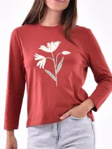 Remera de manga larga color blanco, con cuello redondo y estampa frontal en tono rosado que incluye un diseño de marco con moño y la frase "live simply love sincerely".