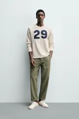 Camiseta relaxed fit de algodón con estructura waffle, color beige. Presenta un parche con el número "29" en azul marino en el pecho. Tiene cuello redondo y manga larga con acabados en rib.