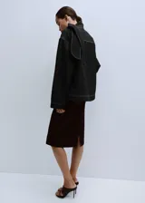 Blusa de mezclilla negra con costuras en contraste, cuello alto y solapa trasera.