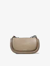 Bolso de hombro color beige, marca JW Anderson, modelo Bumper-12. Confeccionado en cuero con ribetes tubulares acolchados. Tiene correa de hombro ajustable, cierre con cremallera superior y logo estampado en el frente.